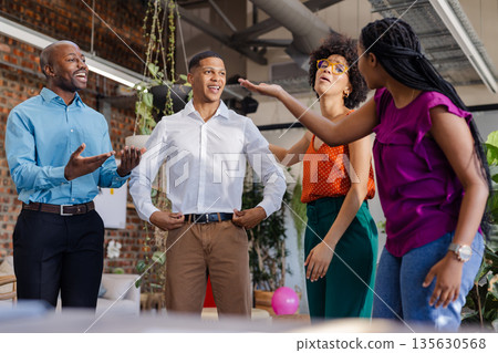 African American colleagues laughing and talking together in modern office setting 135630568