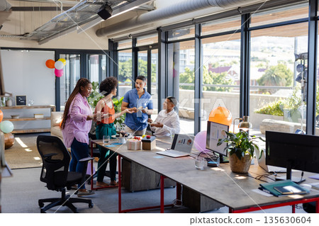 Celebrating teamwork success, African American colleagues with cake in modern office 135630604