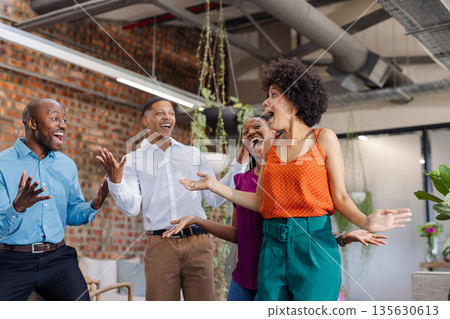 Celebrating success, African American colleagues expressing excitement and joy in modern office 135630613