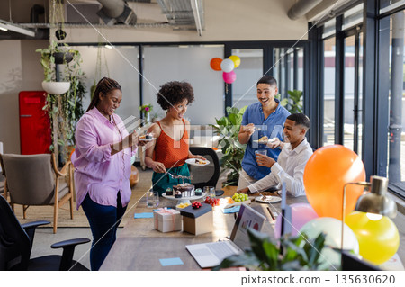 In office, diverse colleagues sharing cake and conversation during work break 135630620