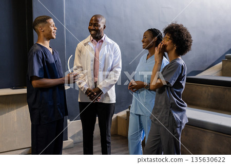 In hospital, African American medical professionals discussing and sharing ideas, smiling together 135630622