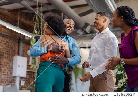 Colleagues celebrating success with joyful hugs and laughter in modern office 135630627