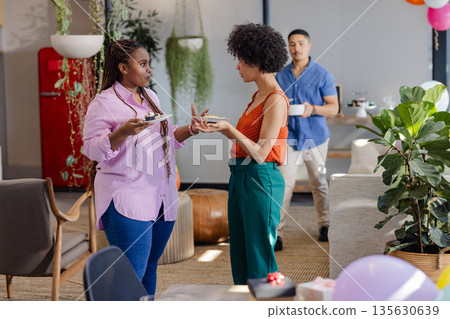 African American woman and colleague discussing work during office coffee break African American woman and colleague discussing work during office coffee break 135630639