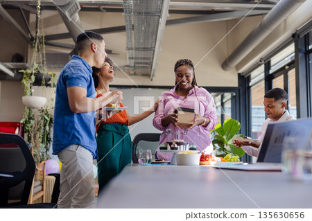 Celebrating in office, colleagues having cake and conversation in modern workspace 135630656