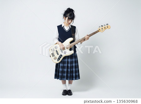 一位可愛的女貝斯手在灰色背景下,神情嚴肅地盯著貝斯指板演奏。 一位可愛的女貝斯手在灰色背景下,神情嚴肅地盯著貝斯指板演奏。 135630968