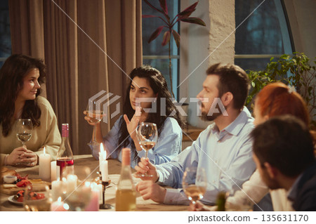 Woman sharing thoughts with friends during wine dinner. Woman sharing thoughts with friends during wine dinner. 135631170