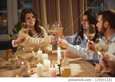 Friends clinking wine glasses during festive home celebration. 135631181