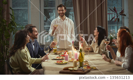 Man standing making toast during group dinner. 135631213