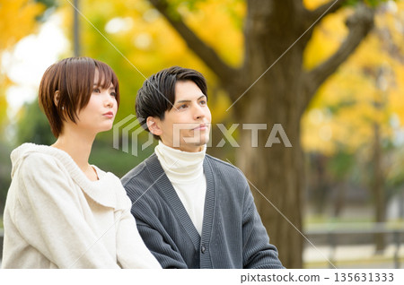 A man and a woman on a date in a park with autumn leaves 135631333