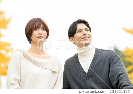 A man and a woman on a date in a park with autumn leaves A man and a woman on a date in a park with autumn leaves 135631335