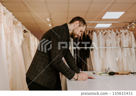 Seamstress creates a sketch in the working notebook. designer draws the clothes and bags. Seamstress creates a sketch in the working notebook. designer draws the clothes and bags. 135631431