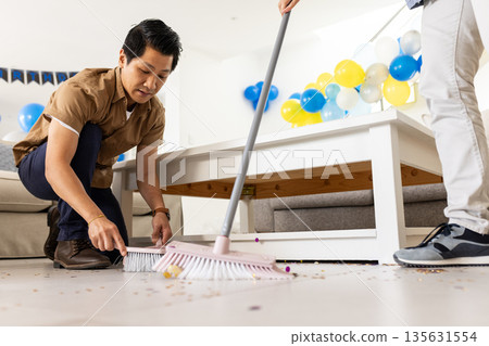 Father and son cleaning living room floor after birthday party celebration 135631554