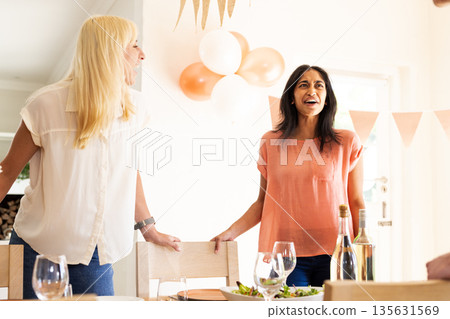 Women joyfully chatting at dining table during wedding celebration at home 135631569