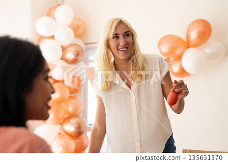 Smiling woman holding party favor at festive wedding celebration with balloons 135631570