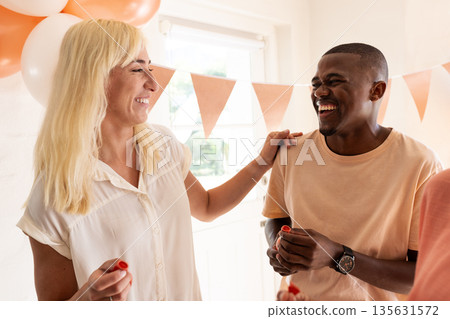 Friends laughing and celebrating together at festive wedding party indoors Friends laughing and celebrating together at festive wedding party indoors 135631572