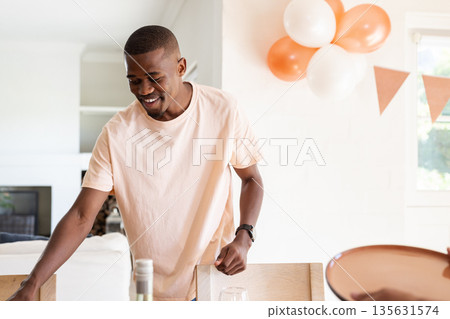 Smiling man arranging table for wedding celebration with balloons in background 135631574