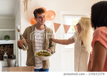 Young man serving salad and wine at festive wedding celebration, smiling joyfully Young man serving salad and wine at festive wedding celebration, smiling joyfully 135631579