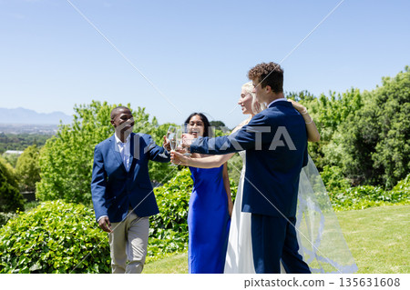 Celebrating wedding outdoors, friends toasting with champagne and smiling together 135631608