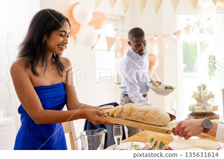 Smiling woman in blue dress serving bread at wedding celebration table Smiling woman in blue dress serving bread at wedding celebration table 135631614