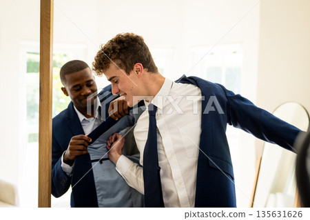 Groom and best man dressing in suits, preparing for wedding ceremony together Groom and best man dressing in suits, preparing for wedding ceremony together 135631626