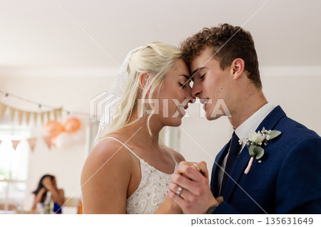 Bride and groom sharing intimate dance, smiling and holding hands at reception 135631649