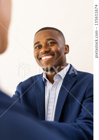 Smiling man in blue suit joyfully greeting guest at wedding celebration Smiling man in blue suit joyfully greeting guest at wedding celebration 135631674