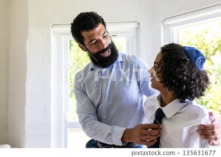 Father helping son with tie, both smiling, preparing for bar mitzvah Father helping son with tie, both smiling, preparing for bar mitzvah 135631677