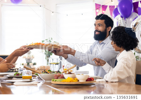 African American man serving food at festive table during family celebration 135631691