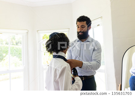 Father helping son with tie at home, preparing for bar mitzvah Father helping son with tie at home, preparing for bar mitzvah 135631703