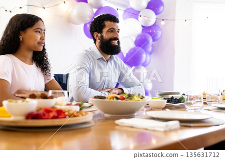Family enjoying festive meal with colorful balloons and decorations in dining room Family enjoying festive meal with colorful balloons and decorations in dining room 135631712