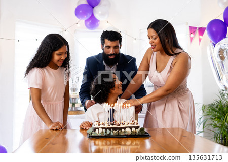 Celebrating birthday, family with cake and festive decorations, smiling at home 135631713