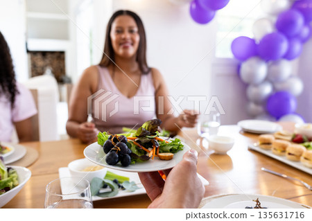 Sharing healthy salad at festive table with smiling African American woman Sharing healthy salad at festive table with smiling African American woman 135631716