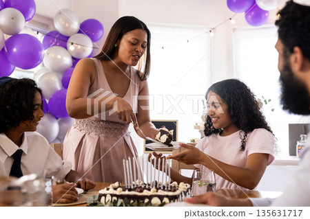 African American family celebrating birthday with cake and balloons at home African American family celebrating birthday with cake and balloons at home 135631717