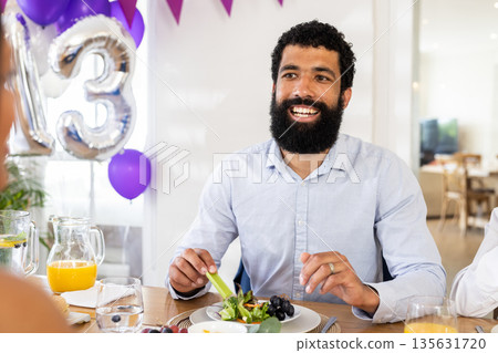 Man enjoying festive meal with friends, smiling and celebrating indoors 135631720