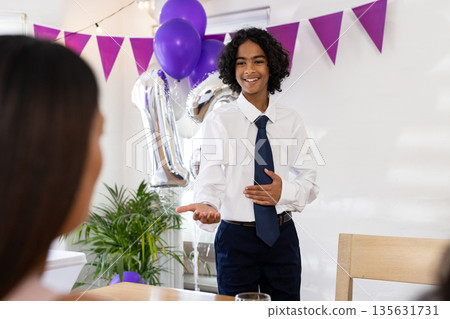 Teen boy in white shirt giving speech at celebration, smiling and gesturing warmly Teen boy in white shirt giving speech at celebration, smiling and gesturing warmly 135631731