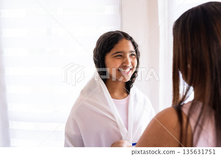 Smiling girl wrapped in white shawl during bar mitzvah at home 135631751