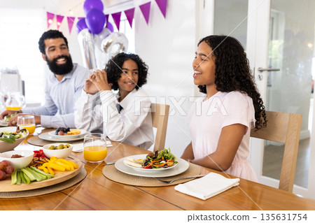 Family enjoying festive meal together, smiling and sharing stories at dining table Family enjoying festive meal together, smiling and sharing stories at dining table 135631754