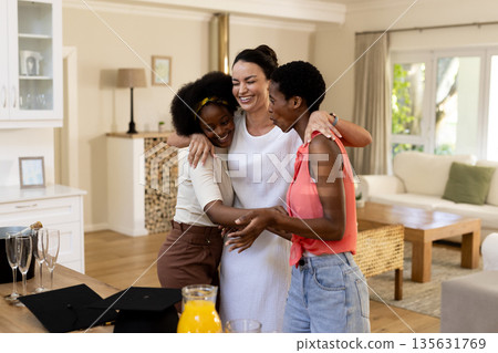 Celebrating friendship, three women hugging and laughing in cozy living room Celebrating friendship, three women hugging and laughing in cozy living room 135631769