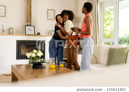 African American friends hugging and smiling in cozy living room, enjoying reunion 135631801