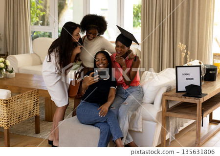 Celebrating school reunion, diverse female friends taking selfie in cozy living room Celebrating school reunion, diverse female friends taking selfie in cozy living room 135631806
