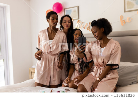 Friends in matching robes taking selfie during birthday celebration at home Friends in matching robes taking selfie during birthday celebration at home 135631826