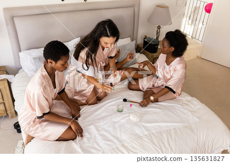 Friends enjoying spa day at home, applying face masks and relaxing together Friends enjoying spa day at home, applying face masks and relaxing together 135631827