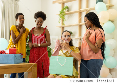 Celebrating at home, diverse female friends enjoying gift exchange and laughter Celebrating at home, diverse female friends enjoying gift exchange and laughter 135631881
