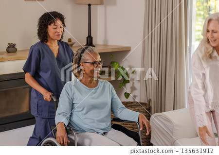 Caregiver assisting senior woman in wheelchair at home, both smiling warmly Caregiver assisting senior woman in wheelchair at home, both smiling warmly 135631912