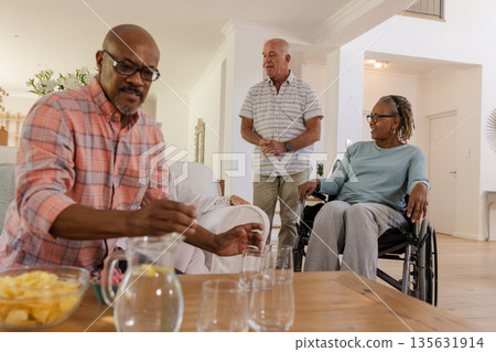 Senior friends enjoying drinks and conversation at home, sharing joyful moments Senior friends enjoying drinks and conversation at home, sharing joyful moments 135631914
