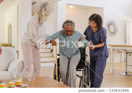 Assisting African American senior woman, caregivers helping transition from wheelchair at home Assisting African American senior woman, caregivers helping transition from wheelchair at home 135631940