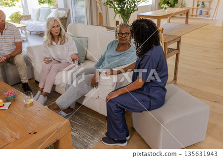 Senior friends discussing health care with nurse at home, sharing concerns 135631943