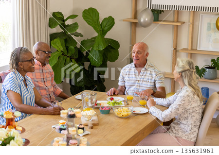 Senior friends enjoying lunch and conversation at home, sharing laughter and stories Senior friends enjoying lunch and conversation at home, sharing laughter and stories 135631961