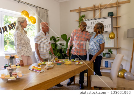 Celebrating retirement, senior friends at home sharing snacks and cheerful conversation 135631993
