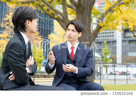 A smiling Japanese man in a suit in an office district A smiling Japanese man in a suit in an office district 135632108